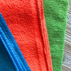 Detalle de textura de paños absorbentes de microfibra en colores azul, naranja y verde