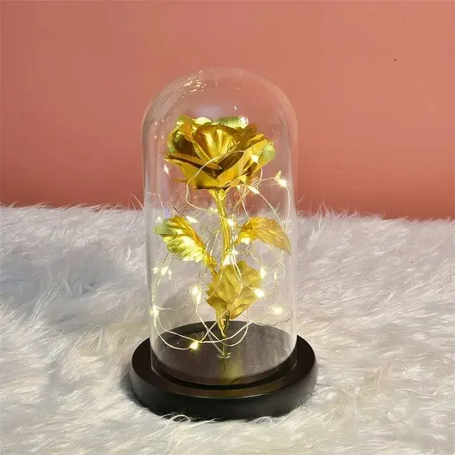 Rosa eterna dorada con luces LED dentro de cúpula de cristal sobre base de madera